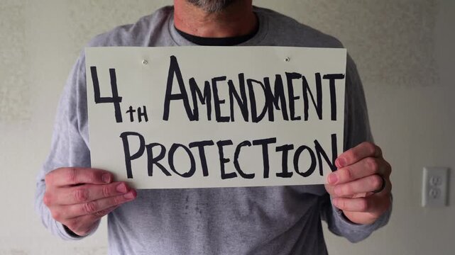 Man attaching protest license plates to vehicle using screwdriver, illustrating citizen pushback against ALPR surveillance - Fourth Amendment privacy