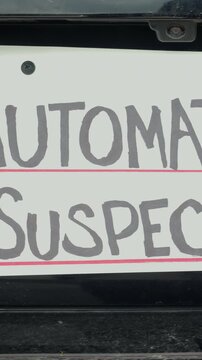Man attaching protest license plates to vehicle using screwdriver, illustrating citizen pushback against ALPR surveillance - Fourth Amendment privacy