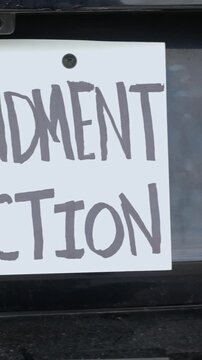 Man attaching protest license plates to vehicle using screwdriver, illustrating citizen pushback against ALPR surveillance - Fourth Amendment privacy