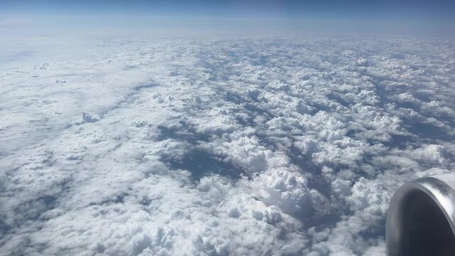 Aerial View Over Fluffy Clouds from Airplane Window