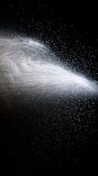 A high-speed capture of a horizontal spray of fine water droplets or mist against a black background.
