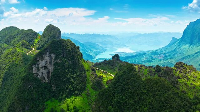 Lush karst peaks and limestone cliffs frame turquoise water and a deep valley in Guizhou, China, offering a scenic travel and nature background.
