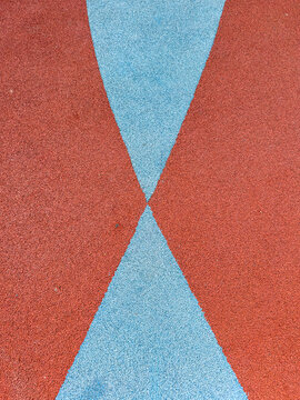 Colorful surface showing blue and red patterns on a playground area in the afternoon sun