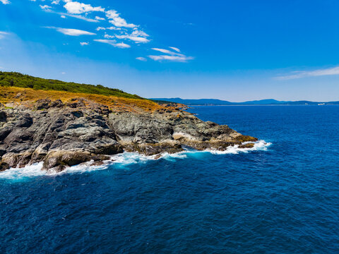 Coastline with rocky cliffs and clear water under blue sky in summer