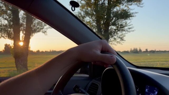a moving car captures a driver's hand resting casually on the steering wheel.