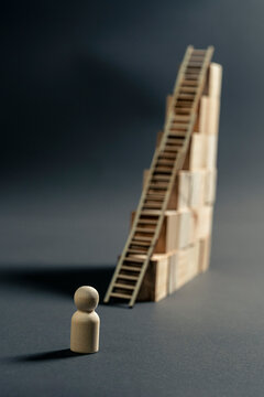 Wooden figurine facing a ladder to overcome a wall as a business challenge and growth concept