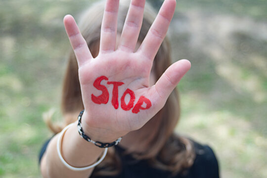 The concept of violence and child abuse. A little girl holds out her hand with the word "STOP." Violence against children.