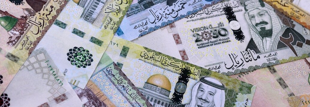Saudi riyal money bills pile on table. Saudi Arabia banknotes of SAR currency close up.