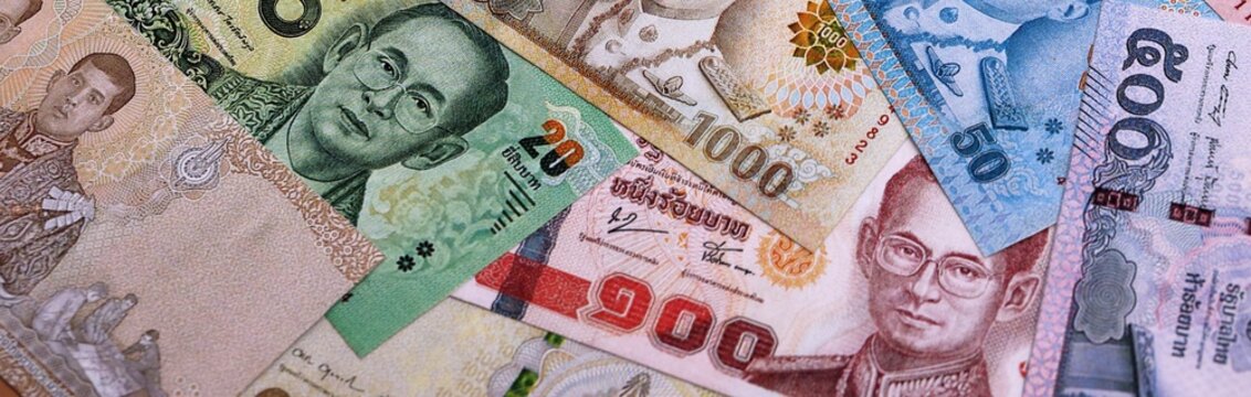 Thai baht money bills pile on table. Thailand banknotes of THB currency close up.