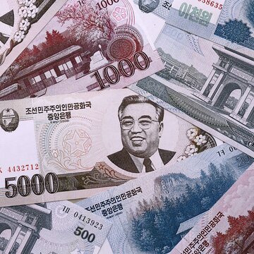North Korean won money bills pile on table. North Korea banknotes of KPW currency close up.