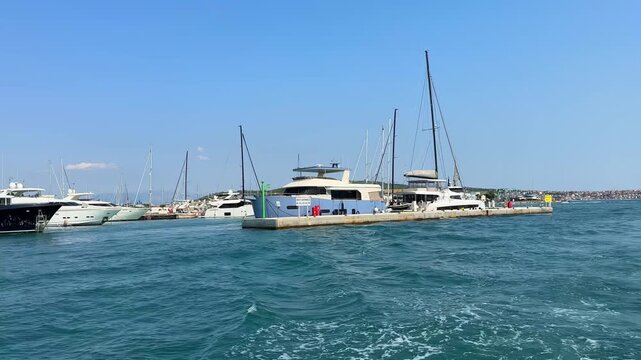 Luxury yachts and sailboats moored at a concrete pier in a sunny marina