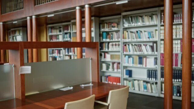Library reading area with bookshelves and study desks, blurred bokeh background interior; background backplate copyspace calm.