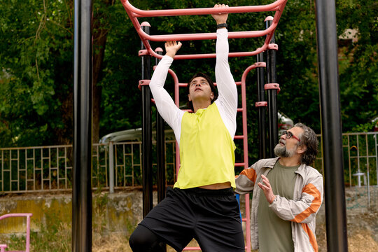 Father encouraging son on monkey bars outdoors