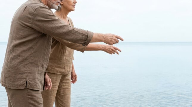 Senior man and woman standing by sea shore and preparing to skip stones on water outdoors.