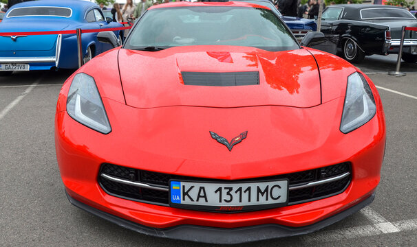 Bright red Chevrolet Corvette C7 sports car features aggressive body styling, black multi spoke wheels, and prominent front fender vents