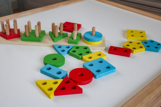 Colorful Montessori wooden shape sorting toy with geometric blocks on a white table.