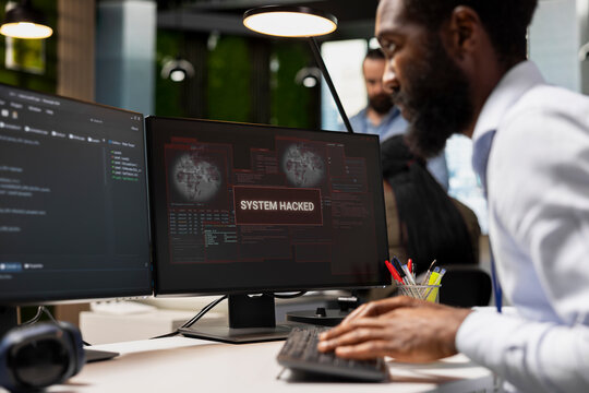 System administrator types on a keyboard to stop a hacker intrusion in an office, responding to a network attack and working to repair the resulting system breach while protecting company systems.