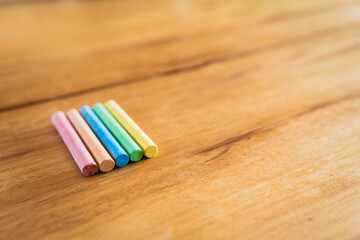 Obraz premium Creative educational design concept: colored pencils and chalk for back to school with a wooden table background