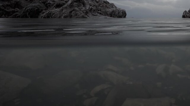 Water surface shows rocks above and below. Clouds cover the sky creating a gray atmosphere. The water is clear enough to see the stones on the bottom.