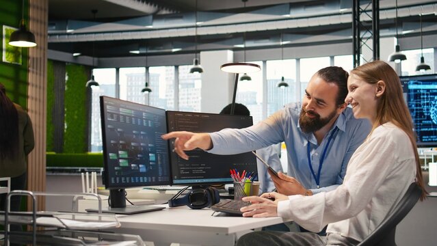 Mentor teaches a young employee to troubleshoot software errors with AI, guiding the junior developer through computer coding, machine learning API development and workplace induction.
