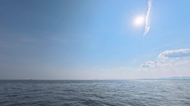 Cinematic real-time video of clear blue sky with distinct contrail over ocean for aviation and journey concept