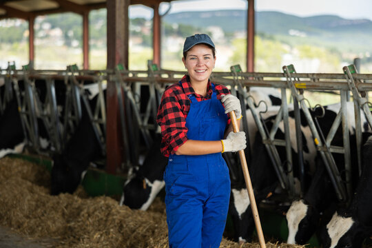 Girl is employee of company during break in work. She stands next to animal pen, with rural hilly landscape in background.