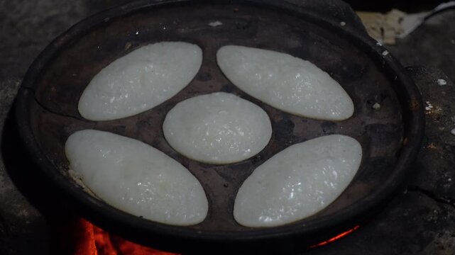 Chitai pitha is being made in a terracotta mold for making pitha in a heated clay oven. Chitai pitha is being made in a five-hole terracotta mold.