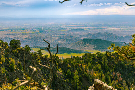 Forested foothills and the wide Gunnison Valley stretch beyond the rim of Black Canyon of the Gunnison NP.
