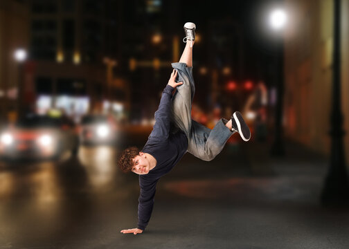 Young man dancing hip-hop on city street at night