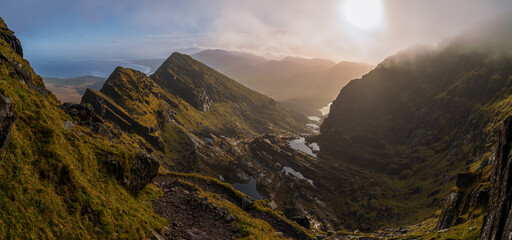 Sunlight breaking through fog over Faha Ridge and glacial lakes on Mount Brandon in Ireland © Ivans
