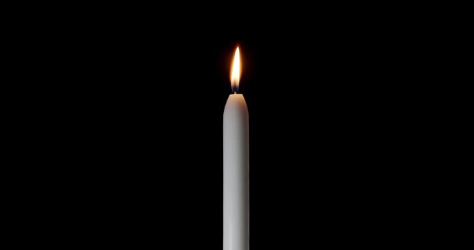 A single candle on a black background. The flame of the candle slowly flickers. One candle slowly flickers, ideal for background or over-layer with blending mode add, screen or lighten.
