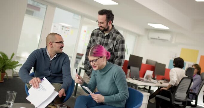 Team members engage in discussion about project details in a busy office setting on a weekday afternoon with clear team collaboration