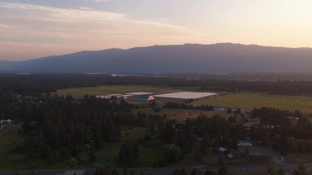 Aerial of rural Idaho landscape near Donnelly with reservoirs and mountains at sunset featuring extensive forests and patches of farmland