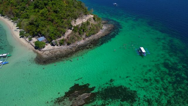 Palawan island hopping with tourists snorkeling in clear water. Smooth aerial view drone