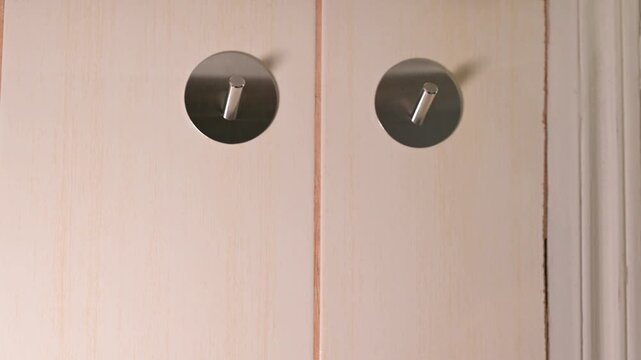 A man taking two purple towels from metal hooks in the kitchen. A hand removes towels from wall hangers one by one, reflecting neatness, kitchen routine and cleanliness