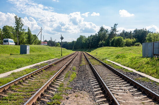 Railway Tracks Leading Through Green Countryside Under Blue Summer Sky.