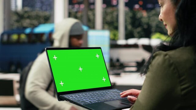 Close-up business traveler using a chroma key laptop in the bus terminal before a work trip, reviewing the journey schedule on a mockup notebook while waiting to travel to the office.