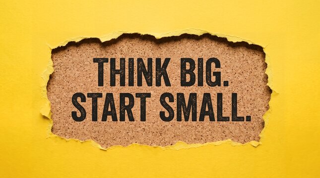 Think big start small motivational quote printed in black text centered on brown cork board visible through torn yellow paper hole opening message typography inspiration goal