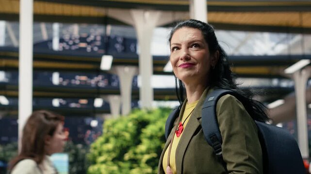 Close-up n upbeat woman holding a mobile phone in the bus station waiting area, reading route information as she walks to the coach platform.