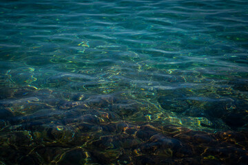 Fototapeta premium Crystal clear water surface texture with sun caustic reflections on the rocky sea floor