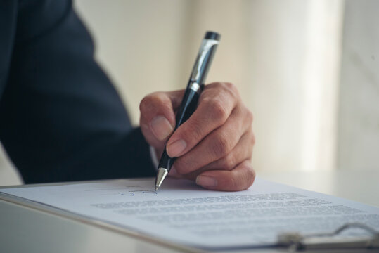 Close up businessman hands writing pen on paper. Man hands writing empty notebook planing meeting agenda on wooden table. Close up man hand write using pen note Personal Organizer sign contract