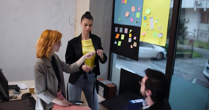Group of people discussing ideas using sticky notes on a wall in an office setting during daytime
