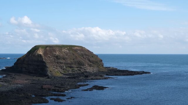 Round Island at The Nobbies on the southwestern tip of Phillip Island, Victoria, Australia.&nbsp;Volcanic rock formation rises out of the blue Southern Ocean along a rugged basalt reef shoreline