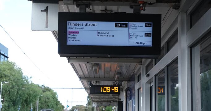 A digital passenger information display screen on platform 1 showing real-time train departures to Flinders Street Station in Melbourne Australia.&nbsp;Electronic timetable hangs beneath a suburban station