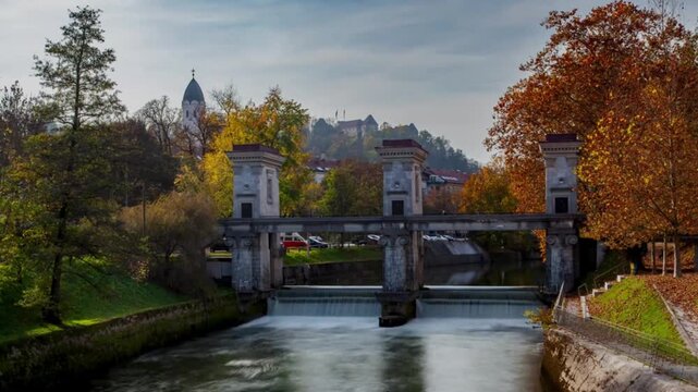 River Sluice Gate Dam and Small Waterfall with Castle on Hill in Autumn