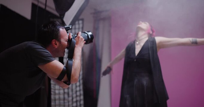 Model poses confidently while photographer captures striking shots in a creative studio environment with colorful backdrop