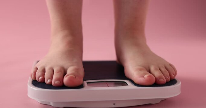 Overweight woman stepping on scale against pink background, closeup