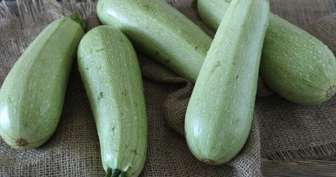 Fresh zucchinis on wooden table, closeup. Camera moving out