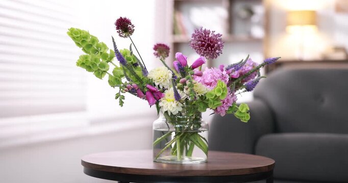 Bouquet of beautiful summer flowers in vase on wooden table indoors, closeup. Camera moving out