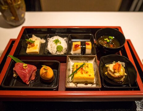 Traditional Japanese kaiseki meal with multiple small dishes featuring seasonal ingredients, artfully arranged on a lacquered tray, elegant fine dining atmosphere, copy space for stock photo